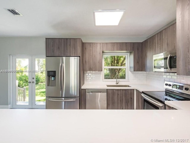 1231 N 16th Ct, Hollywood, FL 33020 - kitchen featuring stainless steel appliances, a sink, light countertops, and decorative backsplash