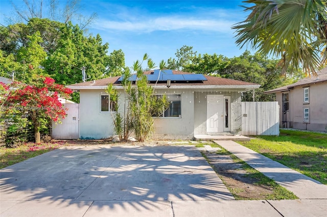 1812 NW 69th Ter, Miami, FL 33147 - view of front facade featuring stucco siding, roof mounted solar panels, and fence
