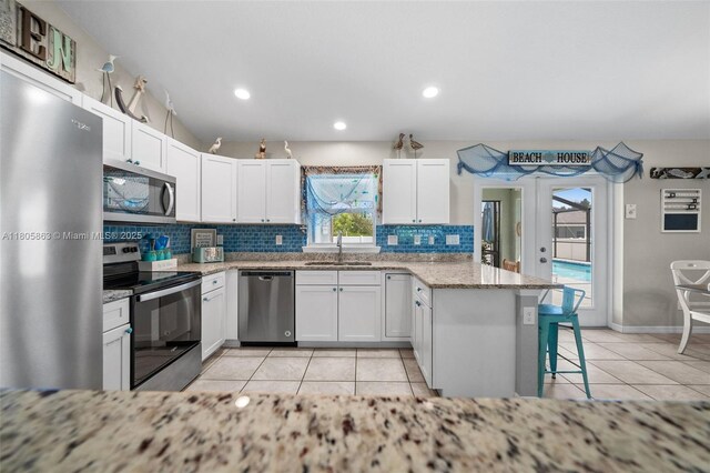 7434 Ashtabula St, Englewood, FL 34224 - kitchen featuring appliances with stainless steel finishes, a peninsula, backsplash, a sink, and light tile patterned floors