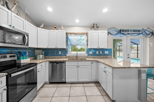7434 Ashtabula St, Englewood, FL 34224 - kitchen featuring appliances with stainless steel finishes, a sink, a peninsula, decorative backsplash, and white cabinets