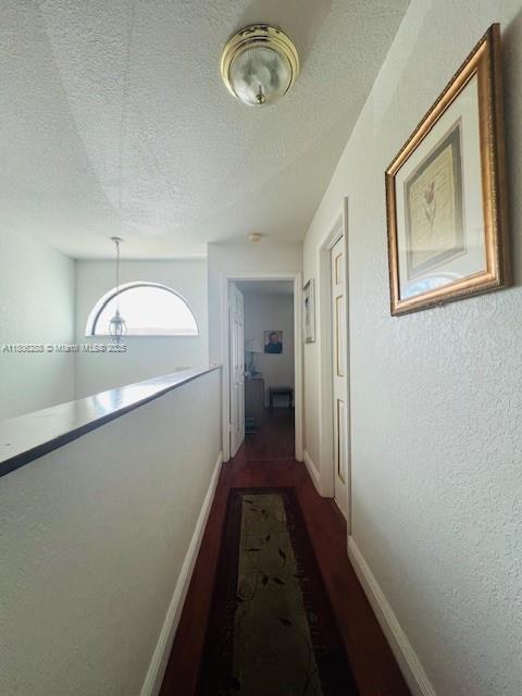 1271 SW 124th Ct Unit 2-D, Miami, FL 33184 - hall with a textured ceiling, a textured wall, dark wood-type flooring, and baseboards