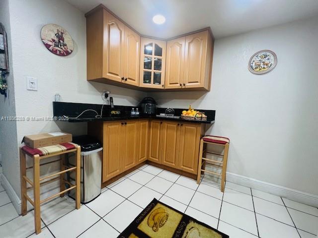 1271 SW 124th Ct Unit 2-D, Miami, FL 33184 - kitchen with baseboards, glass insert cabinets, dark countertops, and light tile patterned floors
