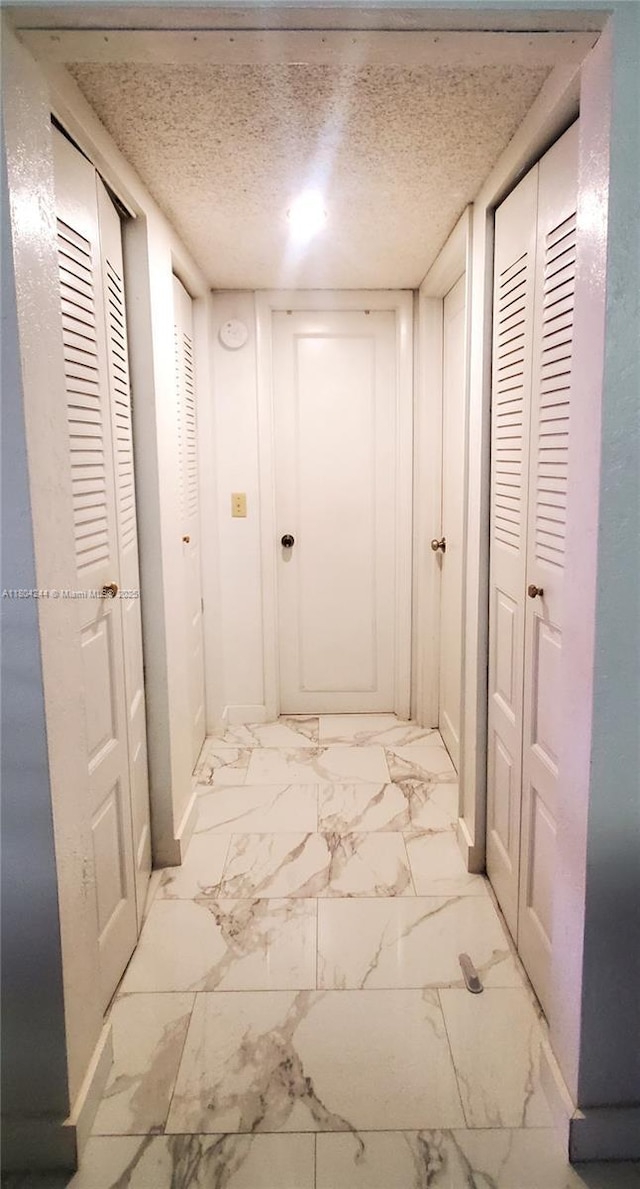 3905 N Nob Hill Rd Unit 510, Sunrise, FL 33351 - corridor featuring baseboards, a textured ceiling, and light marble finish floors