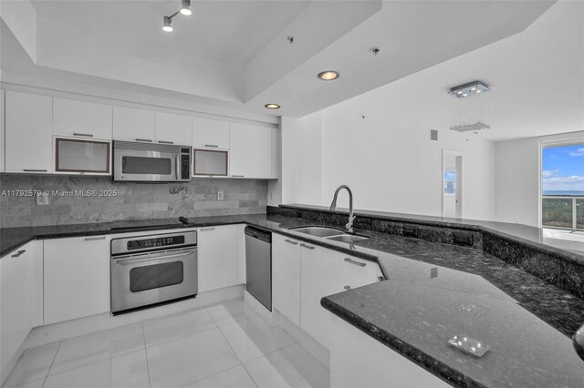 14951 Royal Oaks Ln Unit 2105, North Miami, FL 33181 - kitchen with appliances with stainless steel finishes, a sink, dark stone countertops, white cabinetry, and tasteful backsplash