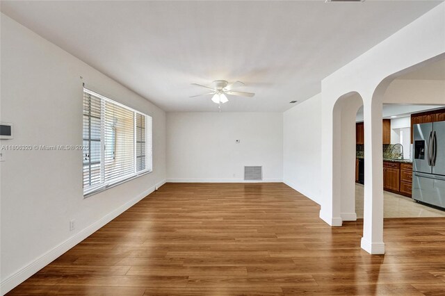 5861 NW 18th Ct, Sunrise, FL 33313 - unfurnished living room featuring a ceiling fan, arched walkways, light wood-type flooring, and baseboards