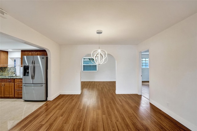 5861 NW 18th Ct, Sunrise, FL 33313 - unfurnished dining area featuring a chandelier, arched walkways, light wood finished floors, and a sink