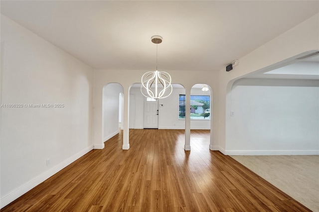 5861 NW 18th Ct, Sunrise, FL 33313 - unfurnished dining area featuring arched walkways, a chandelier, wood finished floors, and baseboards