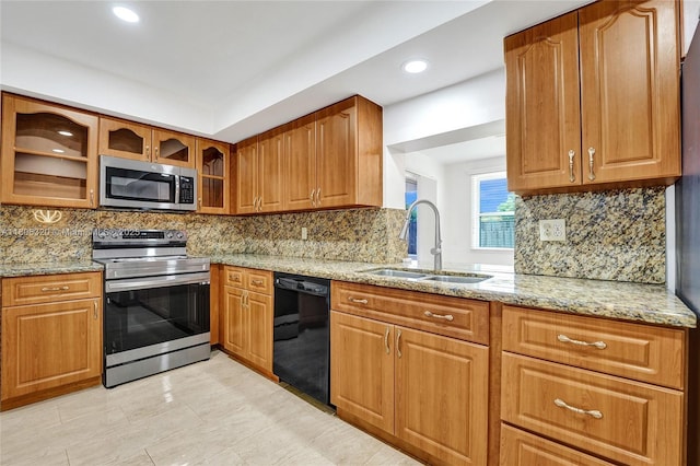 5861 NW 18th Ct, Sunrise, FL 33313 - kitchen featuring appliances with stainless steel finishes, a sink, light stone counters, glass insert cabinets, and brown cabinets