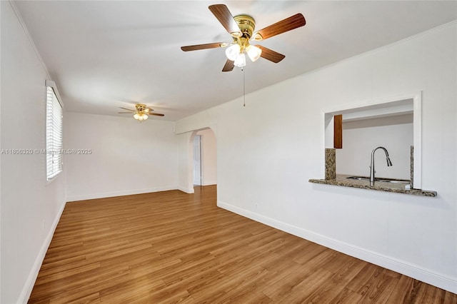 5861 NW 18th Ct, Sunrise, FL 33313 - unfurnished room featuring a ceiling fan, a sink, arched walkways, light wood-style flooring, and baseboards