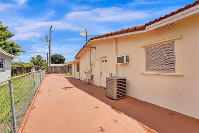 5861 NW 18th Ct, Sunrise, FL 33313 - view of side of property with cooling unit, stucco siding, a fenced backyard, a wall unit AC, and a patio area