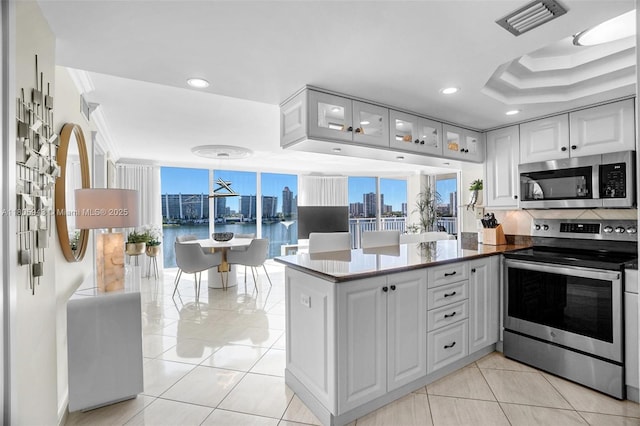 18000 N Bay Rd Unit 803, Sunny Isles Beach, FL 33160 - kitchen with stainless steel appliances, a peninsula, white cabinets, glass insert cabinets, and recessed lighting
