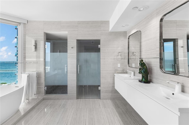 300 S Pointe Dr Unit 2005, Miami Beach, FL 33139 - bathroom with tile walls, double vanity, a stall shower, a freestanding tub, and a water view