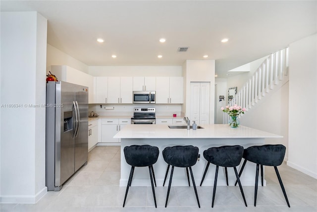 26480 SW 148th Ct Unit 26480, Homestead, FL 33032 - kitchen with stainless steel appliances, a breakfast bar, a kitchen island with sink, light countertops, and white cabinets
