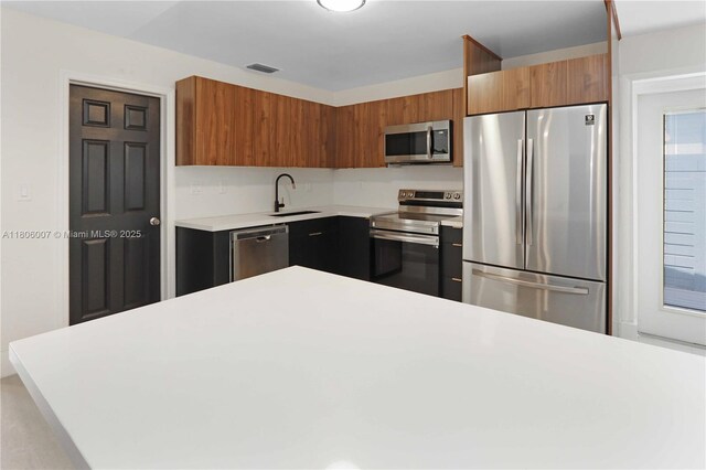1415 Coolidge St, Hollywood, FL 33020 - kitchen featuring appliances with stainless steel finishes, a sink, light countertops, brown cabinetry, and modern cabinets