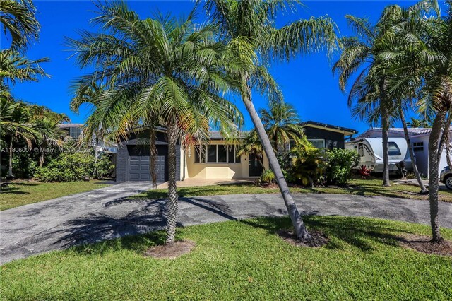 1415 Coolidge St, Hollywood, FL 33020 - obstructed view of property featuring asphalt driveway, a front yard, and stucco siding