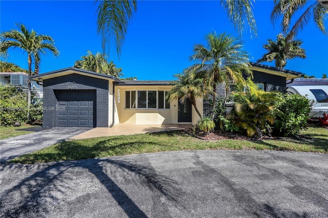 1415 Coolidge St, Hollywood, FL 33020 - single story home featuring an attached garage, asphalt driveway, and stucco siding