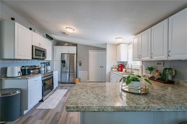 4018 Caloosa Loop, La Belle, FL 33935 - kitchen with appliances with stainless steel finishes, a sink, a peninsula, light wood-type flooring, and white cabinets