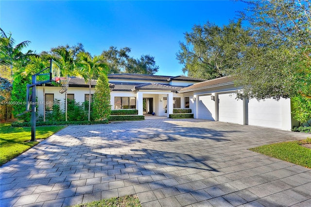 view of front of house featuring a garage, decorative driveway, and stucco siding