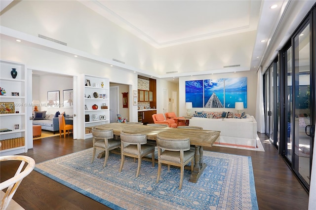 dining space featuring a raised ceiling, dark wood finished floors, recessed lighting, and built in features