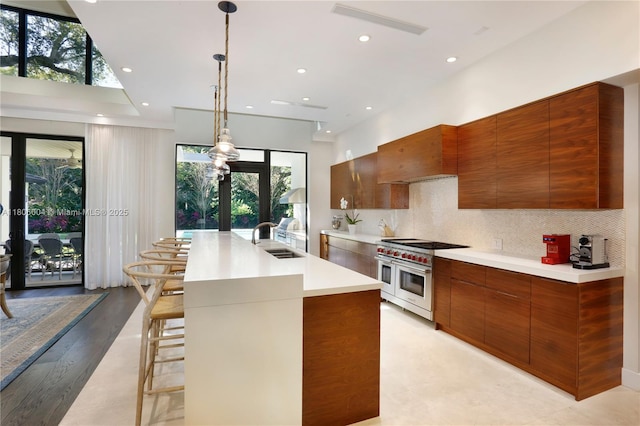 kitchen featuring double oven range, modern cabinets, a sink, brown cabinetry, and light countertops