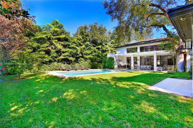 view of grassy yard featuring a patio area and an outdoor pool