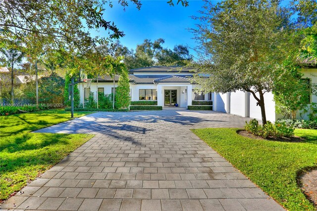 view of front of home with decorative driveway, a front lawn, and stucco siding