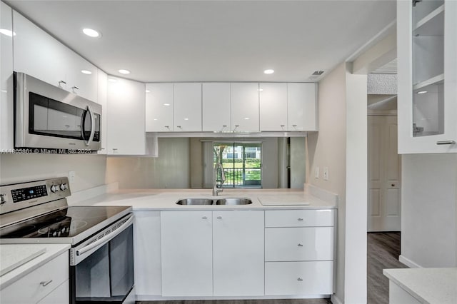 1108 Bahama Bnd Unit B1, Coconut Creek, FL 33066 - kitchen featuring stainless steel appliances, a sink, white cabinetry, light countertops, and glass insert cabinets