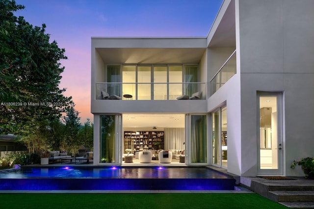 4700 N Meridian Ave, Miami Beach, FL 33140 - back of house at dusk featuring an outdoor hangout area, a balcony, an outdoor pool, and stucco siding