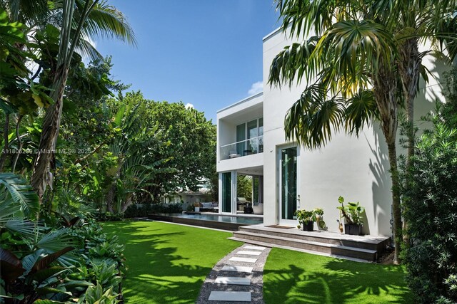 4700 N Meridian Ave, Miami Beach, FL 33140 - back of property featuring stucco siding, a lawn, a patio area, and a balcony
