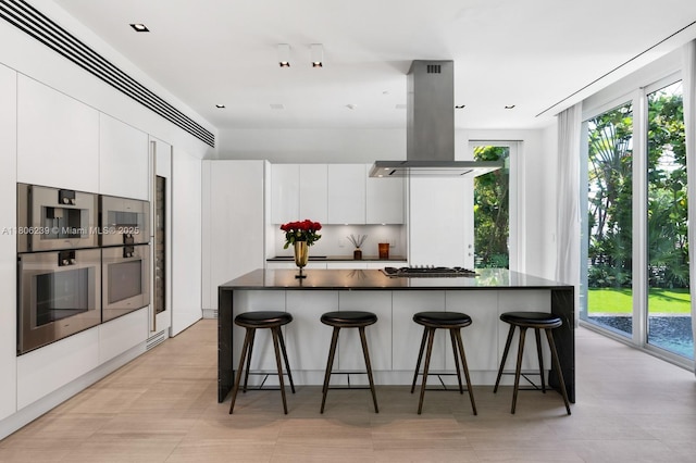 4700 N Meridian Ave, Miami Beach, FL 33140 - kitchen with island exhaust hood, dark countertops, modern cabinets, and a breakfast bar