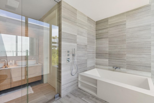 4700 N Meridian Ave, Miami Beach, FL 33140 - bathroom with tile walls, double vanity, a walk in shower, a garden tub, and wood finished floors