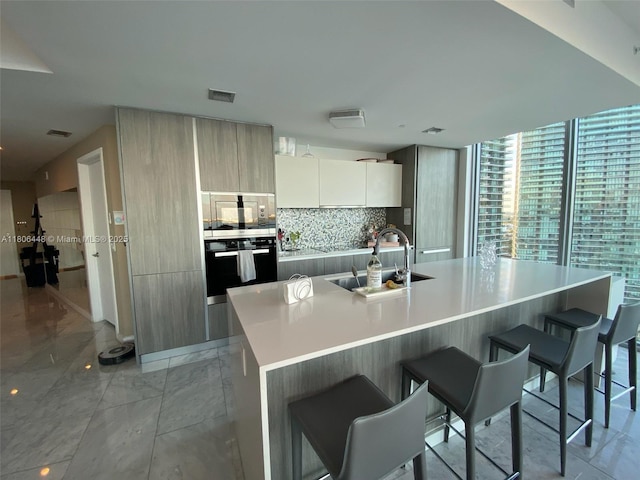 2900 NE 7th Ave Unit 2102, Miami, FL 33137 - kitchen featuring black oven, a sink, modern cabinets, a breakfast bar area, and light countertops