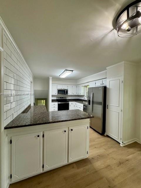 902 Vickie Dr, ,, NC 27511 - kitchen with appliances with stainless steel finishes, a peninsula, light wood-style flooring, white cabinets, and dark stone counters