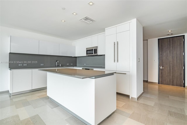88 SW 7th St Unit 2504, Miami, FL 33130 - kitchen featuring stainless steel microwave, a center island, white cabinetry, and light flooring