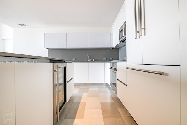 88 SW 7th St Unit 2504, Miami, FL 33130 - kitchen featuring stainless steel appliances, modern cabinets, white cabinets, and beverage cooler