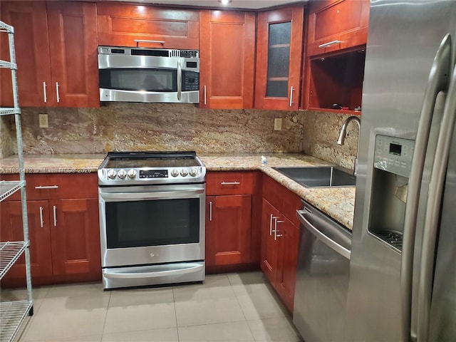 1775 Washington Ave Unit 4A, Miami Beach, FL 33139 - kitchen with stainless steel appliances, a sink, tasteful backsplash, light tile patterned flooring, and glass insert cabinets