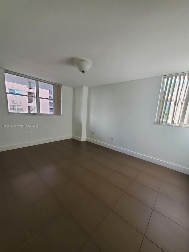 1775 Washington Ave Unit 4A, Miami Beach, FL 33139 - empty room with healthy amount of natural light, baseboards, and dark tile patterned floors