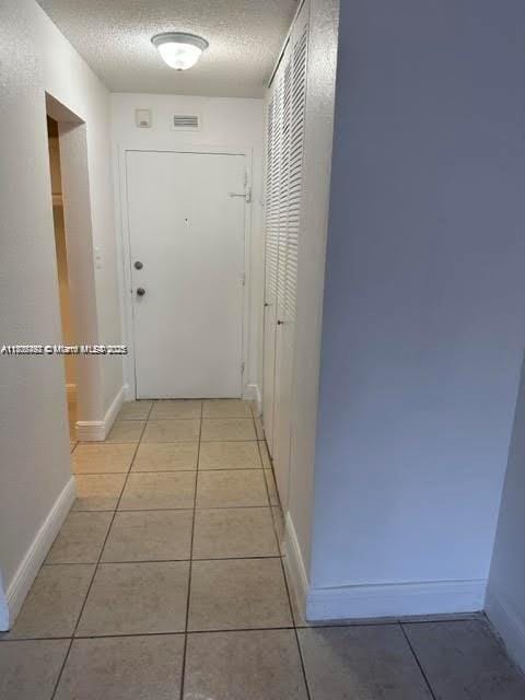 1800 Sans Souci Blvd Unit 115, North Miami, FL 33181 - hall featuring light tile patterned floors, a textured ceiling, and baseboards
