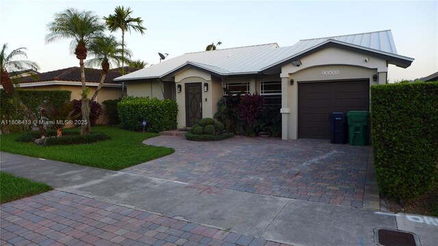 14430 SW 108th St, Miami, FL 33186 - ranch-style house featuring stucco siding, decorative driveway, an attached garage, metal roof, and a front yard