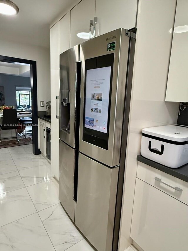 8992 Palm Tree Ln Unit 8992, Pembroke Pines, FL 33024 - kitchen with stainless steel fridge, light marble finish floors, white cabinetry, and dark countertops