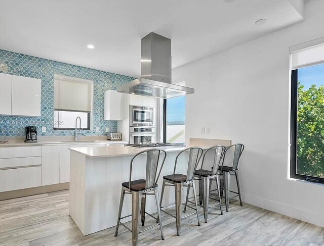 332 Balboa St, Hollywood, FL 33019 - kitchen with island exhaust hood, a sink, appliances with stainless steel finishes, a kitchen breakfast bar, and modern cabinets