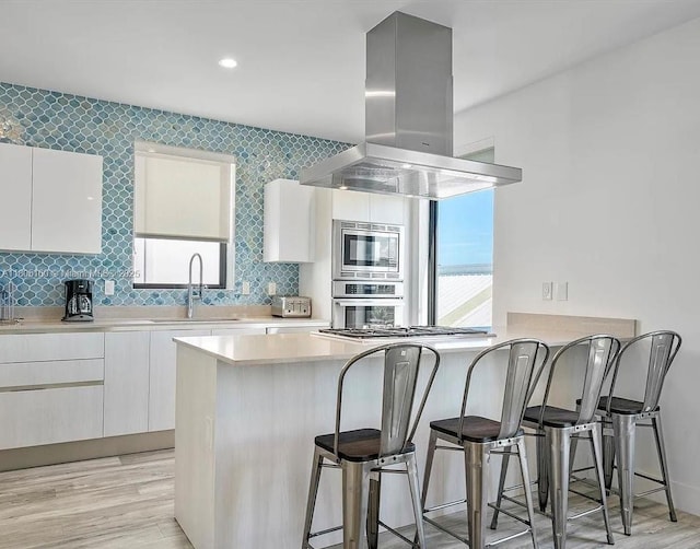 332 Balboa St, Hollywood, FL 33019 - kitchen with island exhaust hood, a sink, a kitchen breakfast bar, modern cabinets, and white cabinets