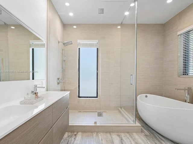 332 Balboa St, Hollywood, FL 33019 - bathroom featuring a shower stall, a freestanding tub, double vanity, wood finished floors, and tile walls