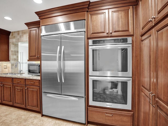 3401 NE 21st Ave, Lighthouse Point, FL 33064 - kitchen with appliances with stainless steel finishes, a sink, tasteful backsplash, brown cabinetry, and recessed lighting