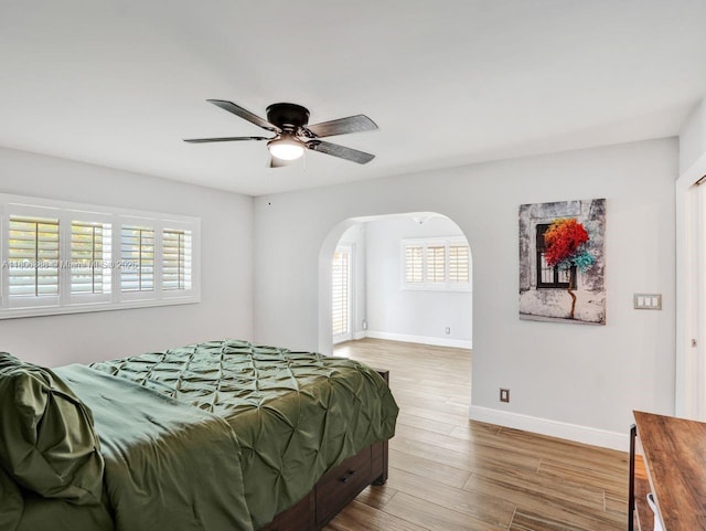 3401 NE 21st Ave, Lighthouse Point, FL 33064 - bedroom featuring arched walkways, baseboards, wood finished floors, and a ceiling fan