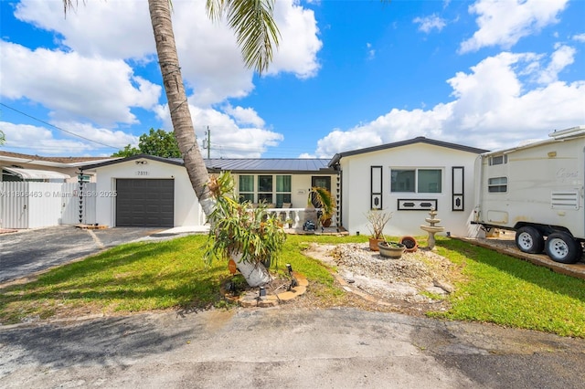 7311 Biltmore Blvd, Miramar, FL 33023 - single story home with a garage, stucco siding, asphalt driveway, metal roof, and a gate