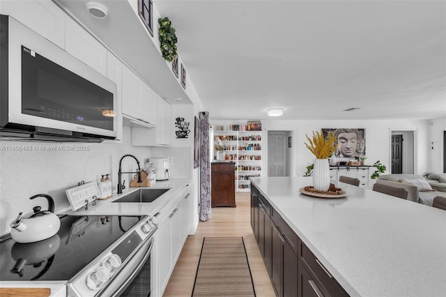 7311 Biltmore Blvd, Miramar, FL 33023 - kitchen with stainless steel electric range oven, a sink, white cabinetry, and light countertops