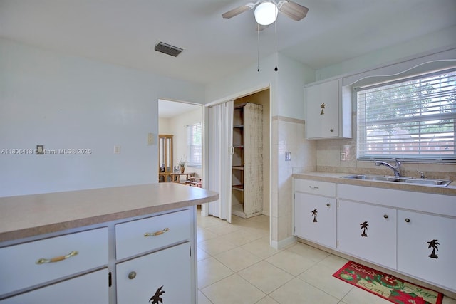 210 Joe Hilton St, Avon Park, FL 33825 - kitchen with a sink, light tile patterned floors, light countertops, ceiling fan, and white cabinets