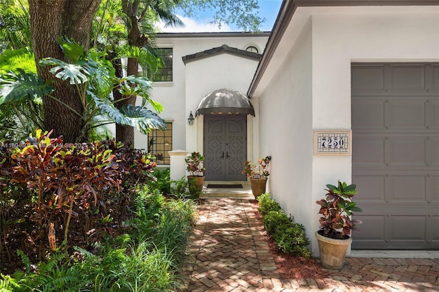 doorway to property with a garage and stucco siding