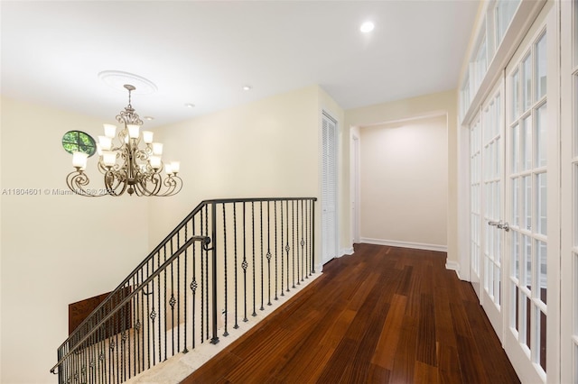 hall featuring wood finished floors, a chandelier, baseboards, an upstairs landing, and recessed lighting